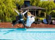 bride and groom jump at pool at airbnb wedding