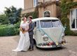 groom and bride next to their vintage wedding car
